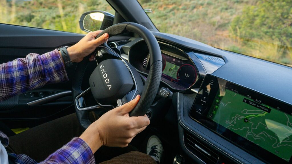 Řidič za volantem vozu Škoda, který využívá systém Start-Stop v městském provozu.